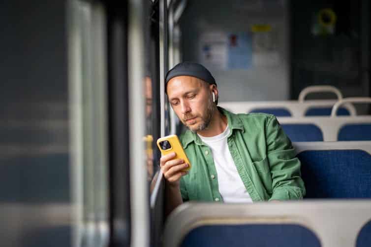 A man on public transport looking at a smartphone.