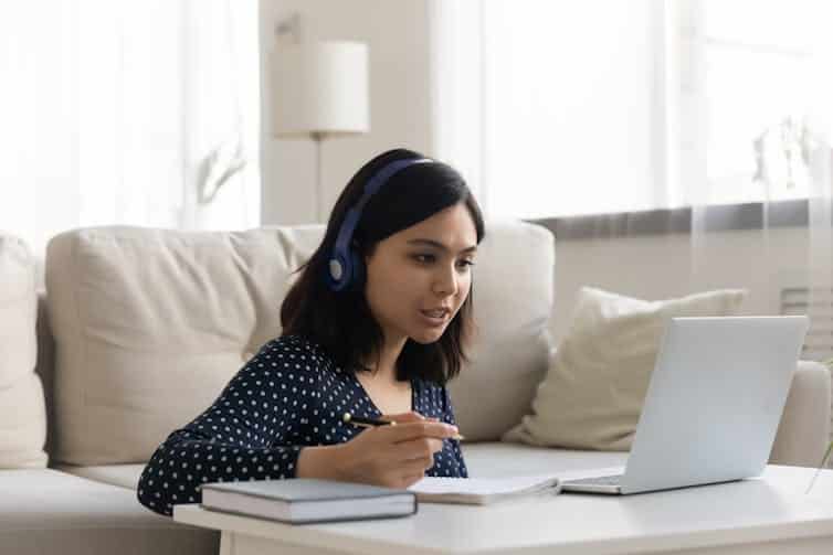 A woman wearing headphones looking at a laptop screen